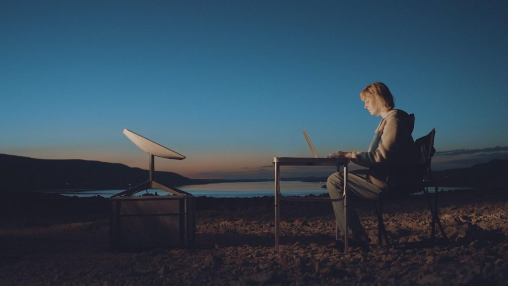 Starlink satellite dish next to woman on laptop.