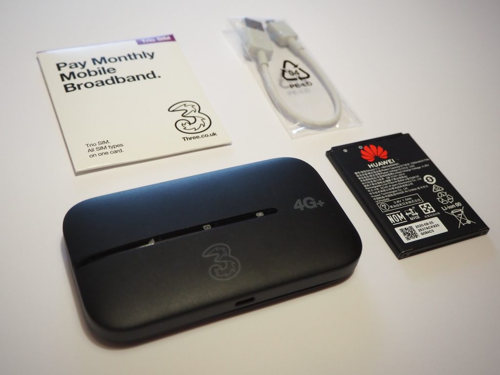 A MiFi device from Three, with included accessories.