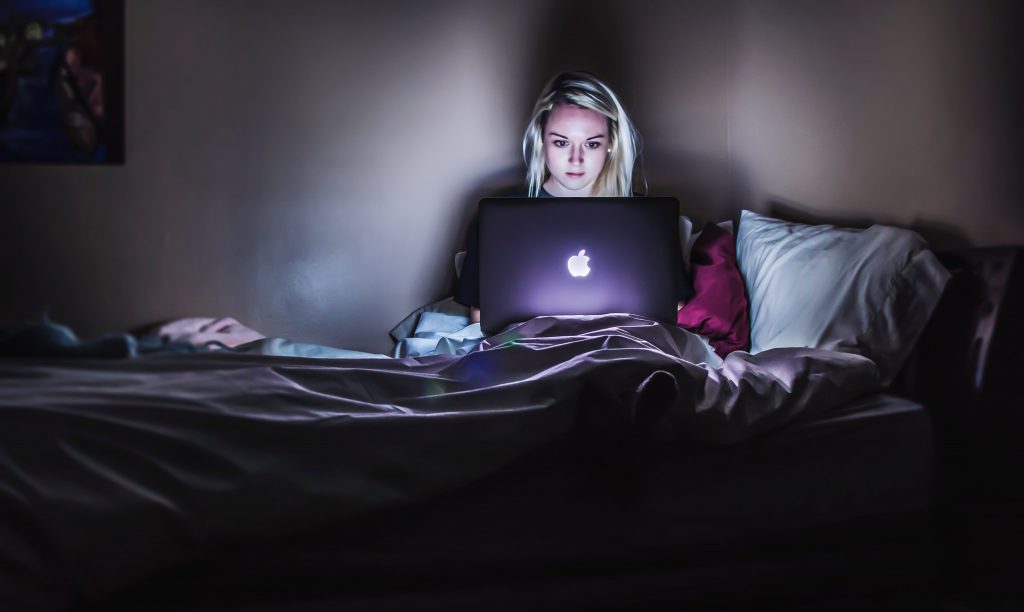 Student watching Netflix on Macbook in bed.