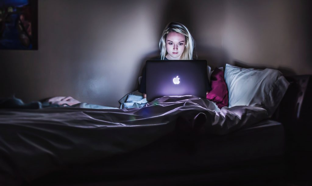 Woman watching Netflix in bed.